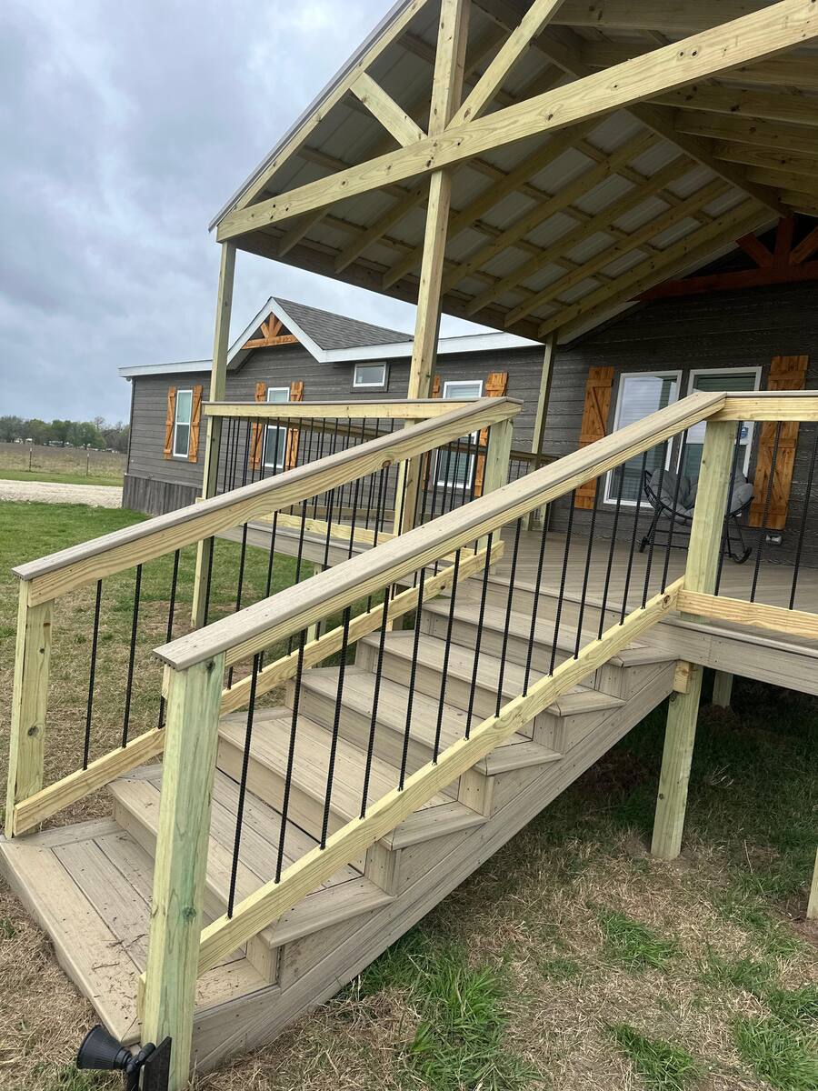 Covered backyard porch with metal railings